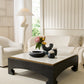 Modern living room with a white sofa, coffee table, and decorative items.