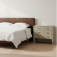 Bedroom with wooden bed and nightstand against a white wall