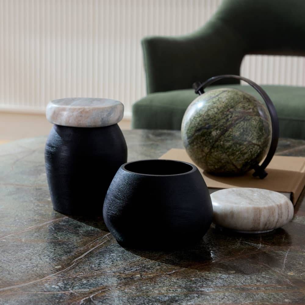 Decorative vases and a globe on a marble surface with a blurred background