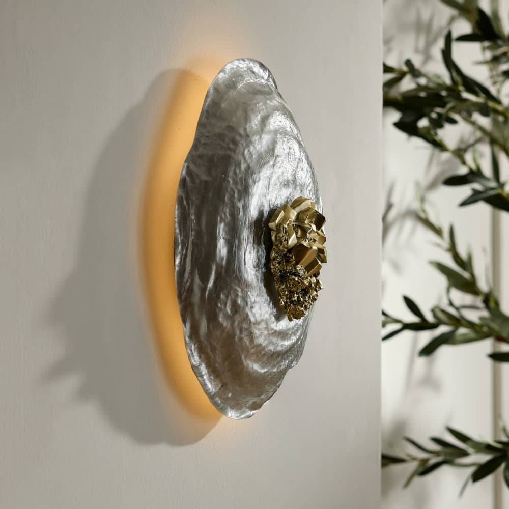 Decorative wall light fixture with a textured surface and gold accent on a neutral background.