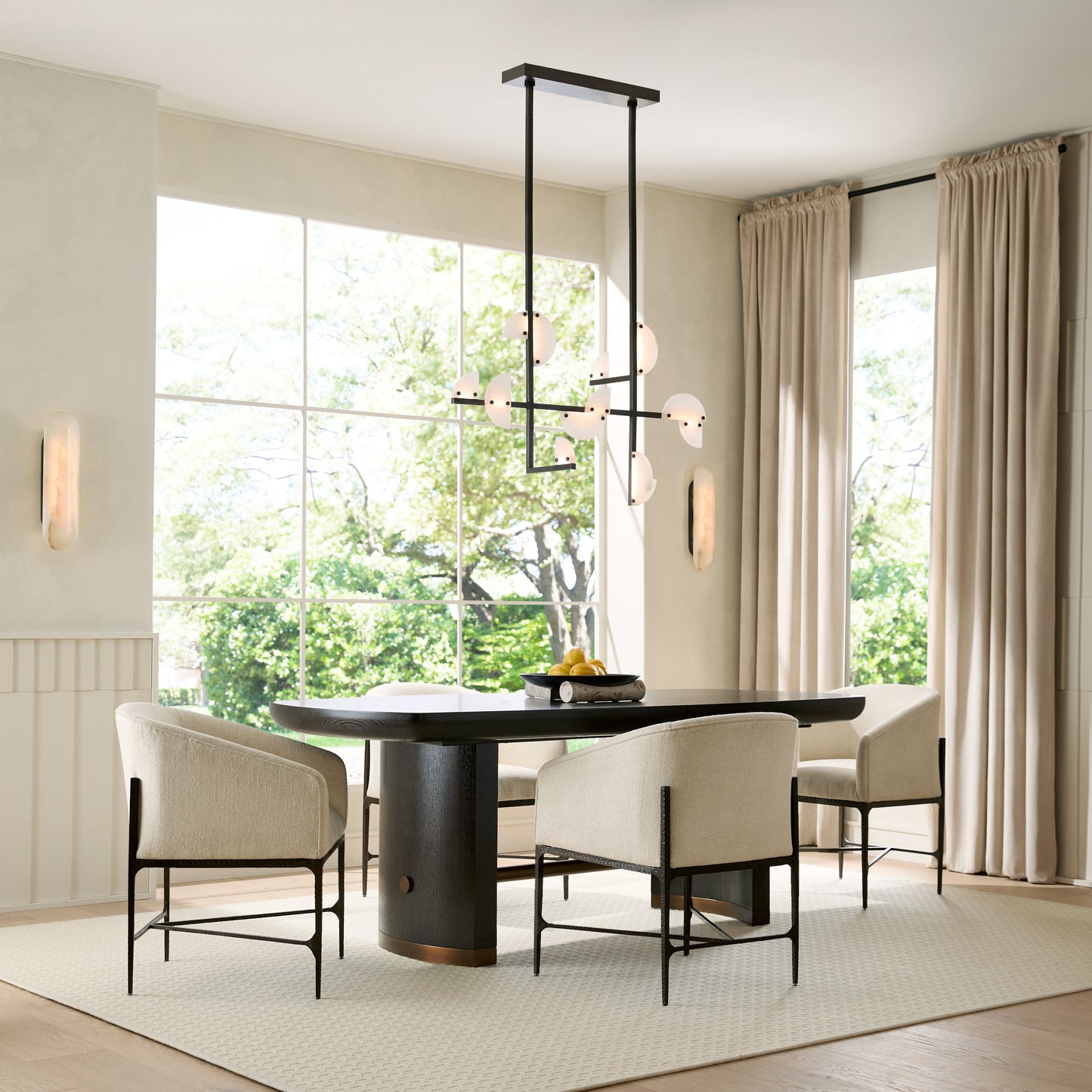 Modern dining room with a black round table and white chairs, large windows, and light-colored curtains.
