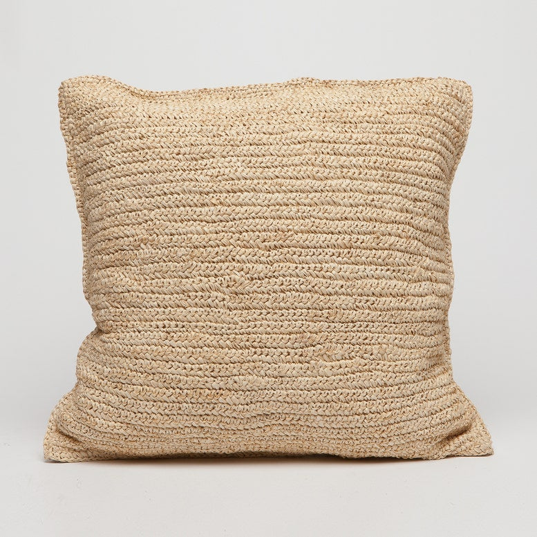 A square woven throw pillow in a natural beige jute or seagrass material, shown against a plain light gray background.