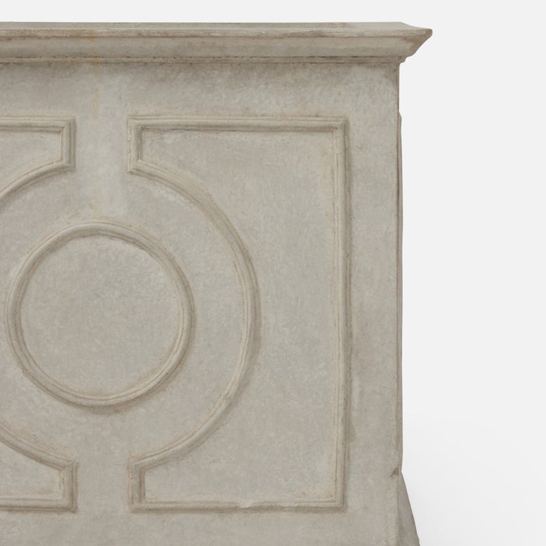 Close-up of a light gray stone or concrete decorative wall panel with embossed geometric and circular patterns, shown against a plain white background.