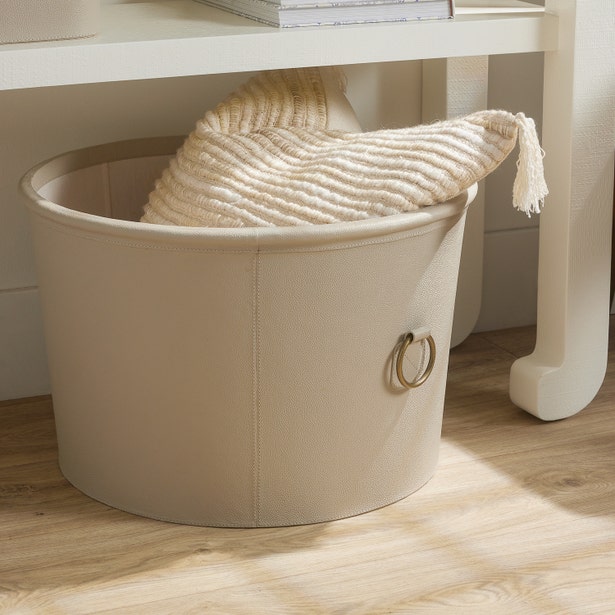 light gray laundry basket with a woven lid on a wooden floor