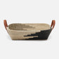 Woven basket with black and beige pattern and brown leather handles on a white background
