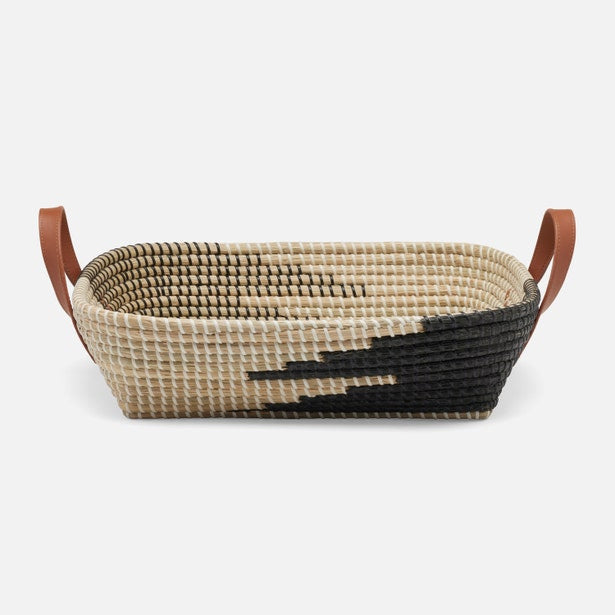 Woven basket with black and beige pattern and brown leather handles on a white background