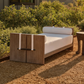 Wooden outdoor sofa with white cushions in a garden setting