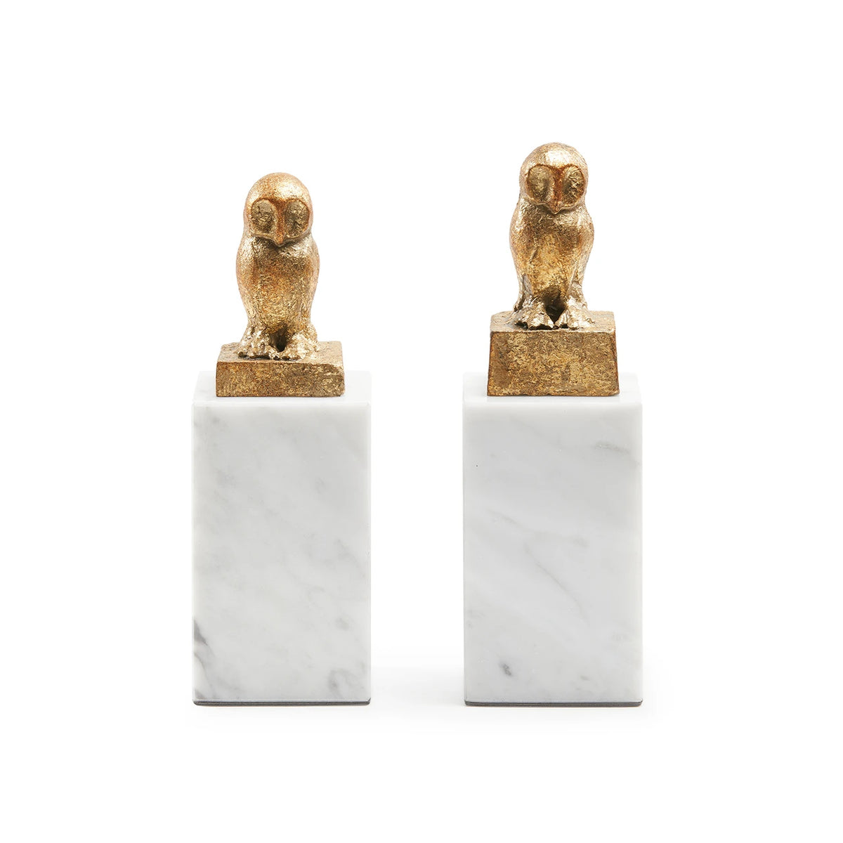 Two gold owl sculptures on white marble bases against a white background