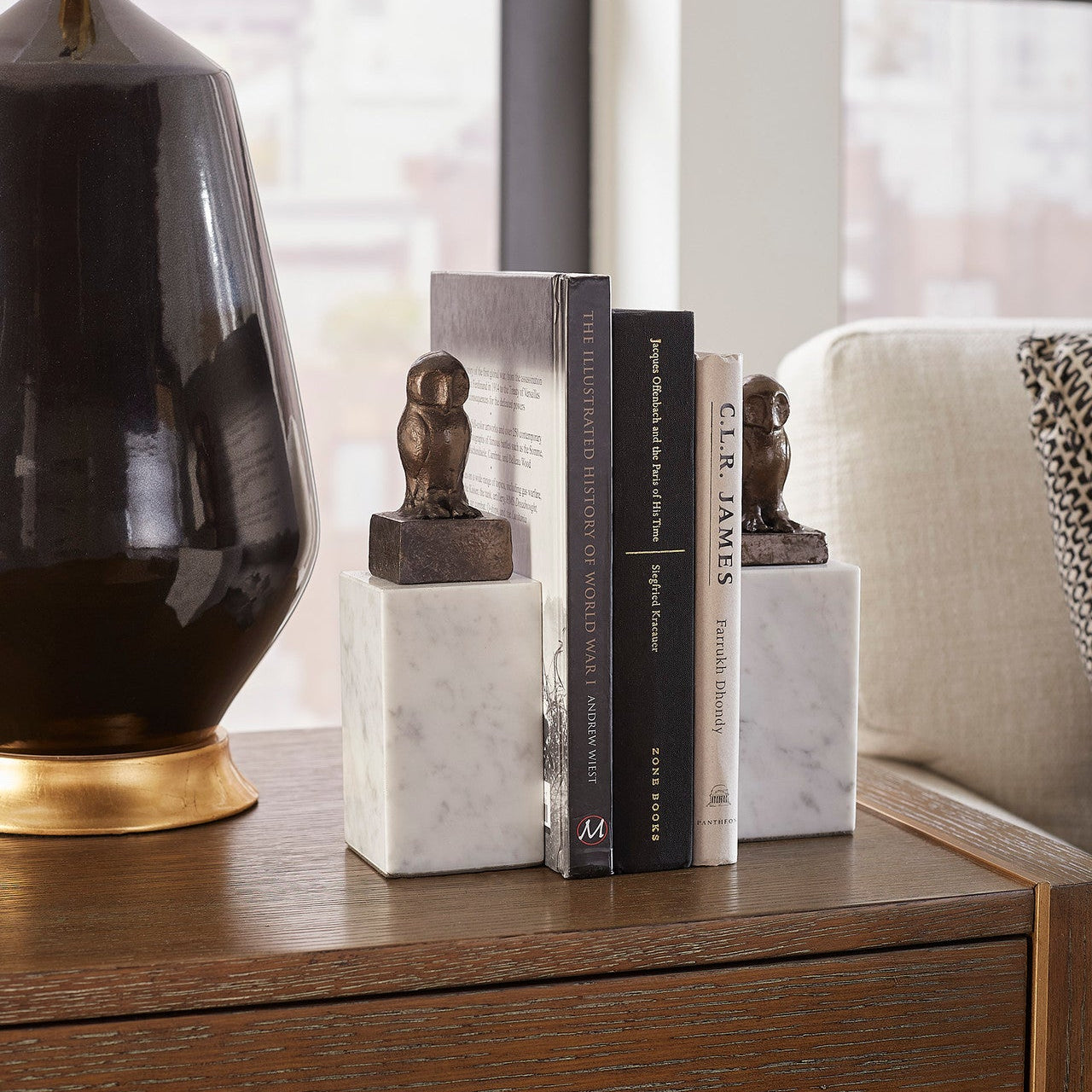 Decorative books with marble bases and small statues on a wooden surface.