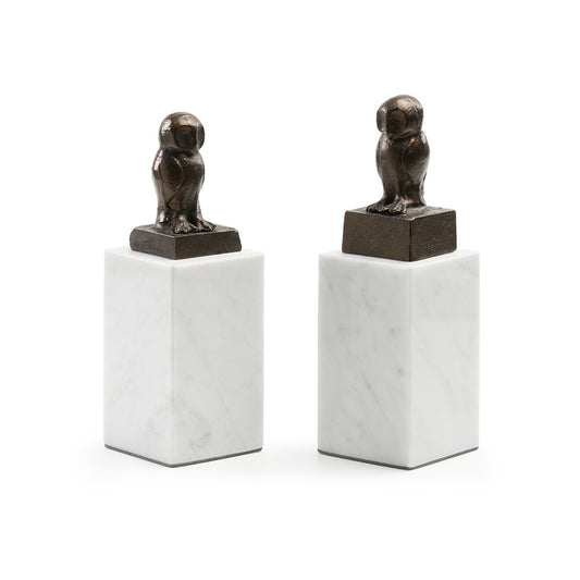 Two bronze owl sculptures on marble bases against a white background