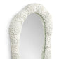 Oval mirror with a textured white frame on a white background