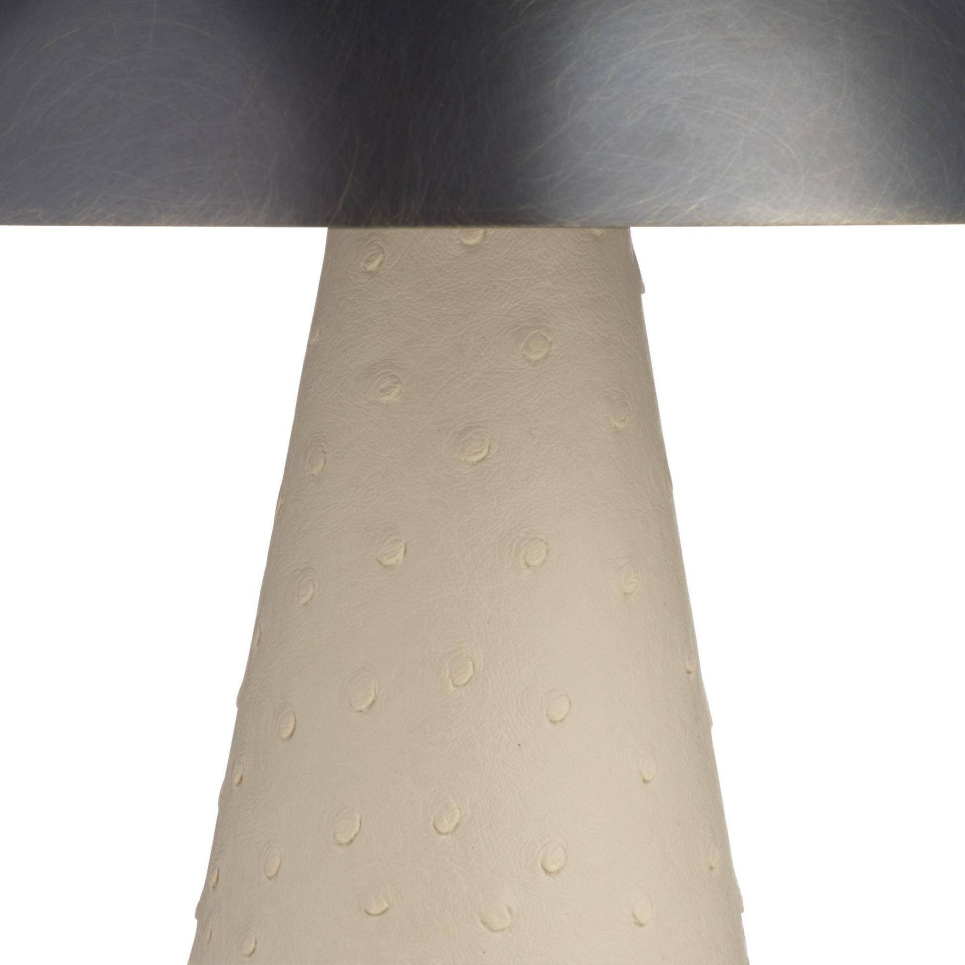 Close-up of a lamp with a metallic base and beige lampshade on a white background