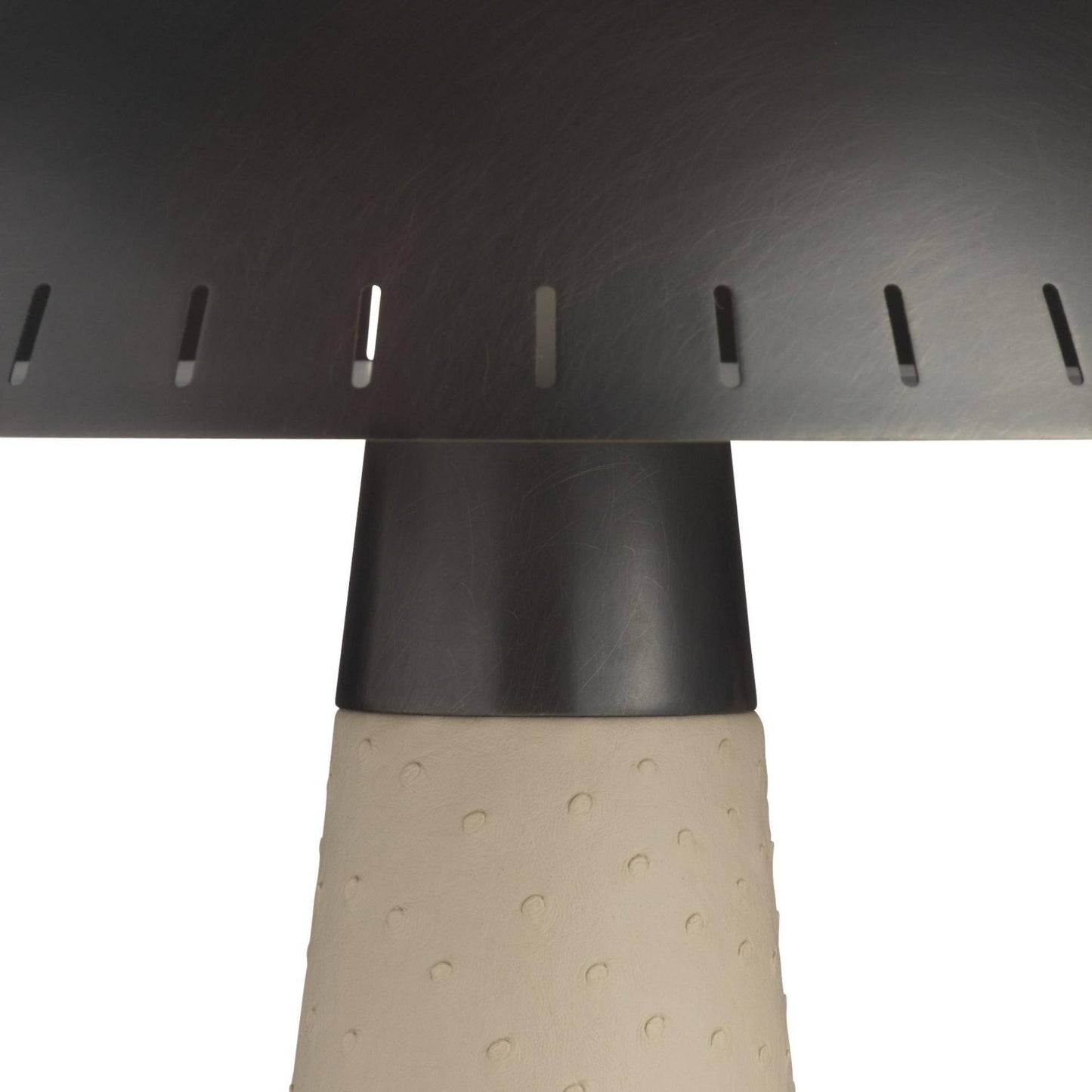 Close-up of a dark metal table or chair leg with a perforated top surface and a textured beige cylindrical base on a white background.