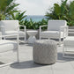 A round pouf ottoman with a thick, textured woven or braided fabric in a light gray color, shown against a plain white background.