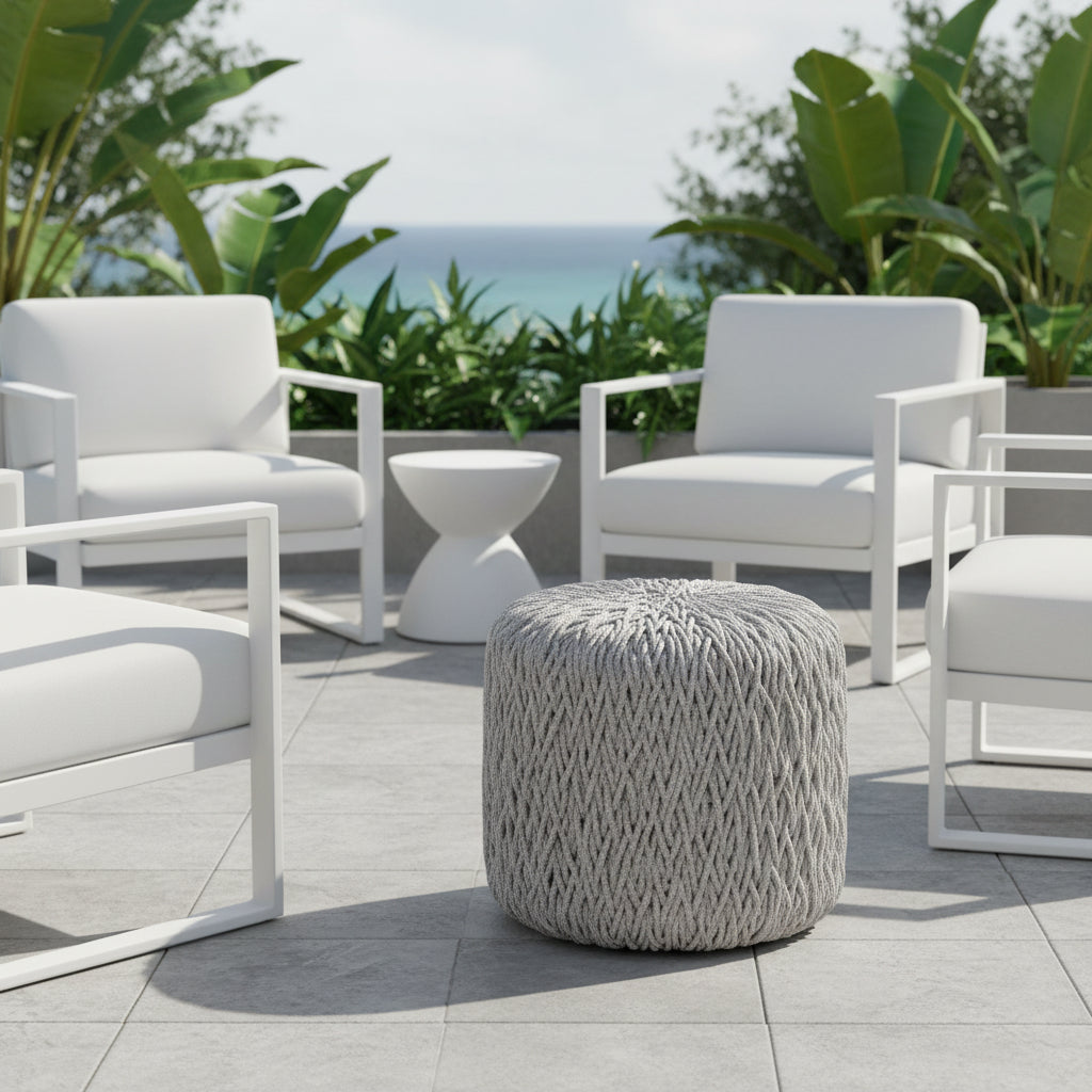 A round pouf ottoman with a thick, textured woven or braided fabric in a light gray color, shown against a plain white background.
