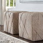 Two beige textured ottomans on a wooden floor with a neutral background