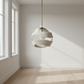 Modern pendant light hanging in a minimalistic room with large windows.