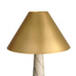 Gold lampshade on a marble base against a white background