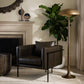 Modern living room with a brown leather armchair, floor lamp, and decorative plant.