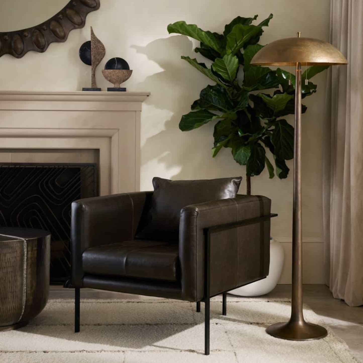 Modern living room with a brown leather armchair, floor lamp, and decorative plant.