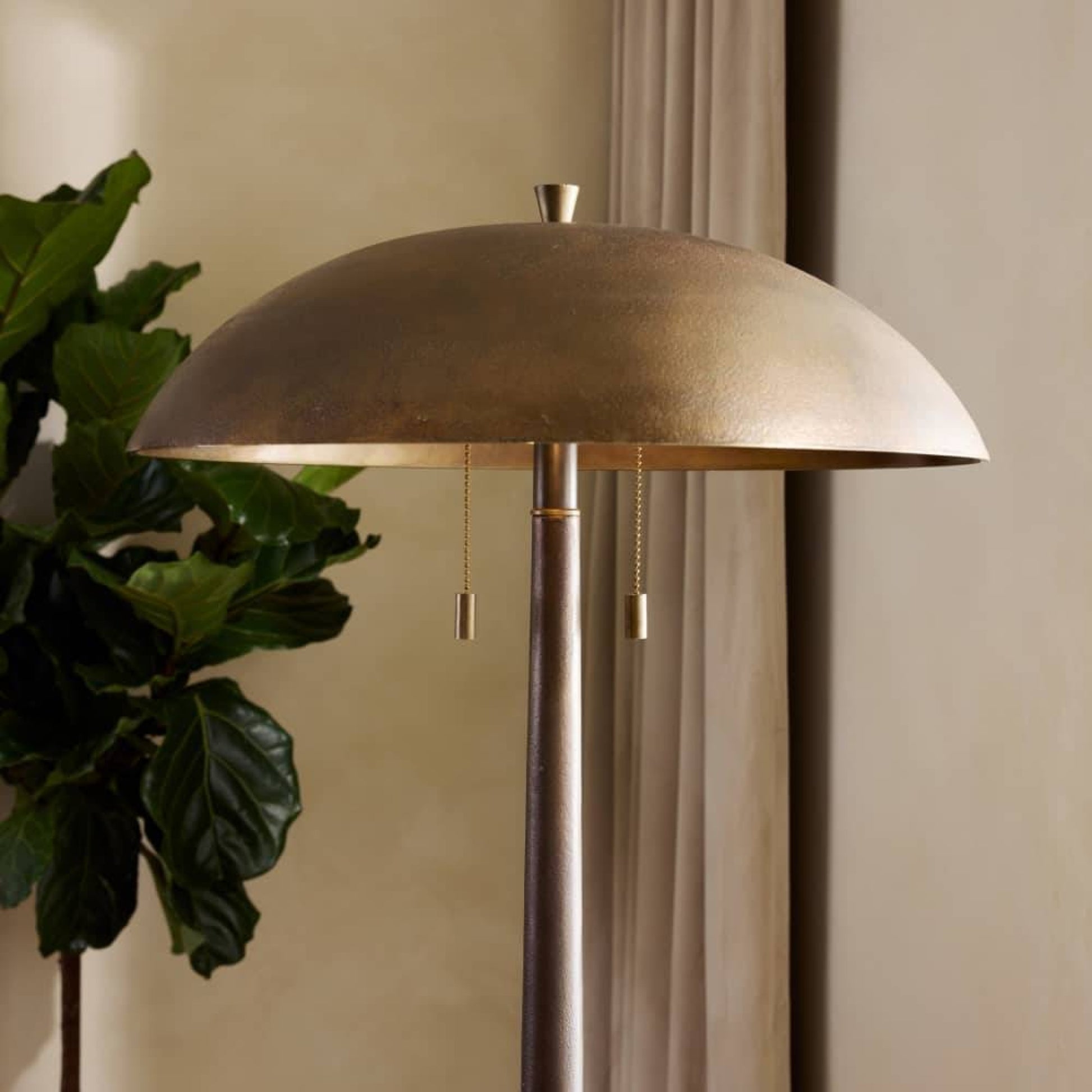 Bronze floor lamp with a plant on a beige background