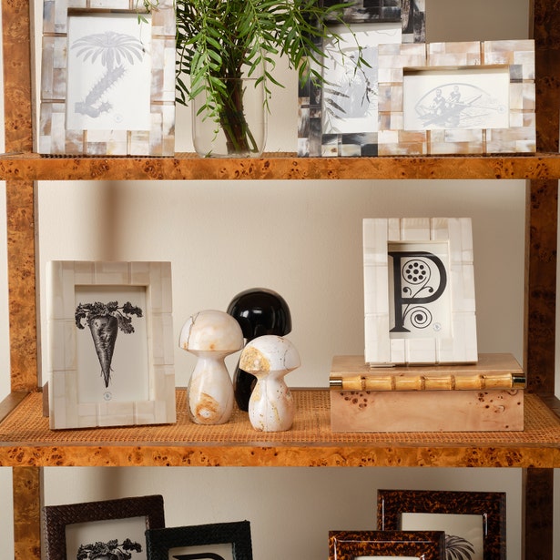 Decorative shelf with framed pictures, a vase, and decorative items against a neutral wall.