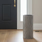 A tall, cylindrical ceramic vase with a textured wood grain pattern in gray and black, shown on a light gray background.
