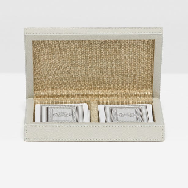 Open beige fabric box with playing cards on a white background