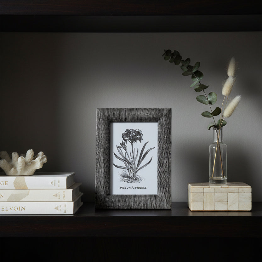 A small rectangular picture frame with a textured dark gray shagreen border, holding a white card with a black-and-white botanical illustration and the text 'Pigeon & Poole'.