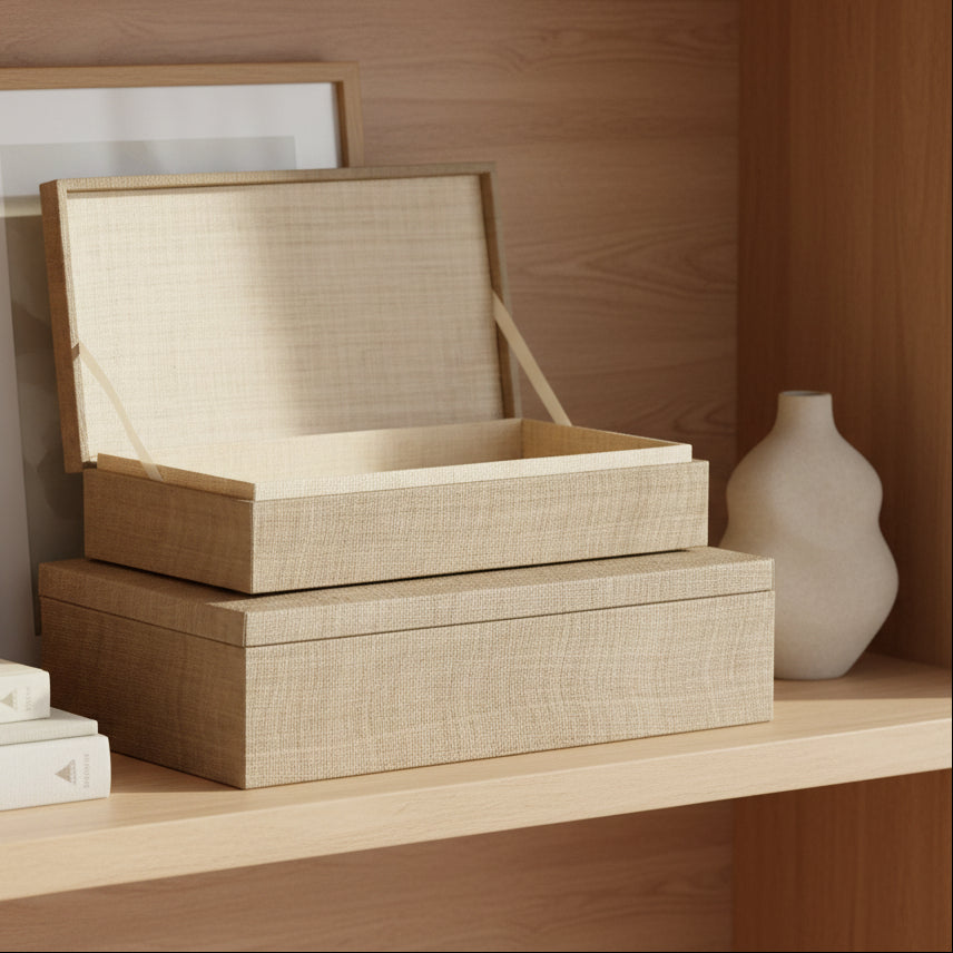 Two stacked rectangular storage boxes with a woven natural fiber texture, shown on a clean white background. The top box has its lid propped open, revealing a light beige interior.