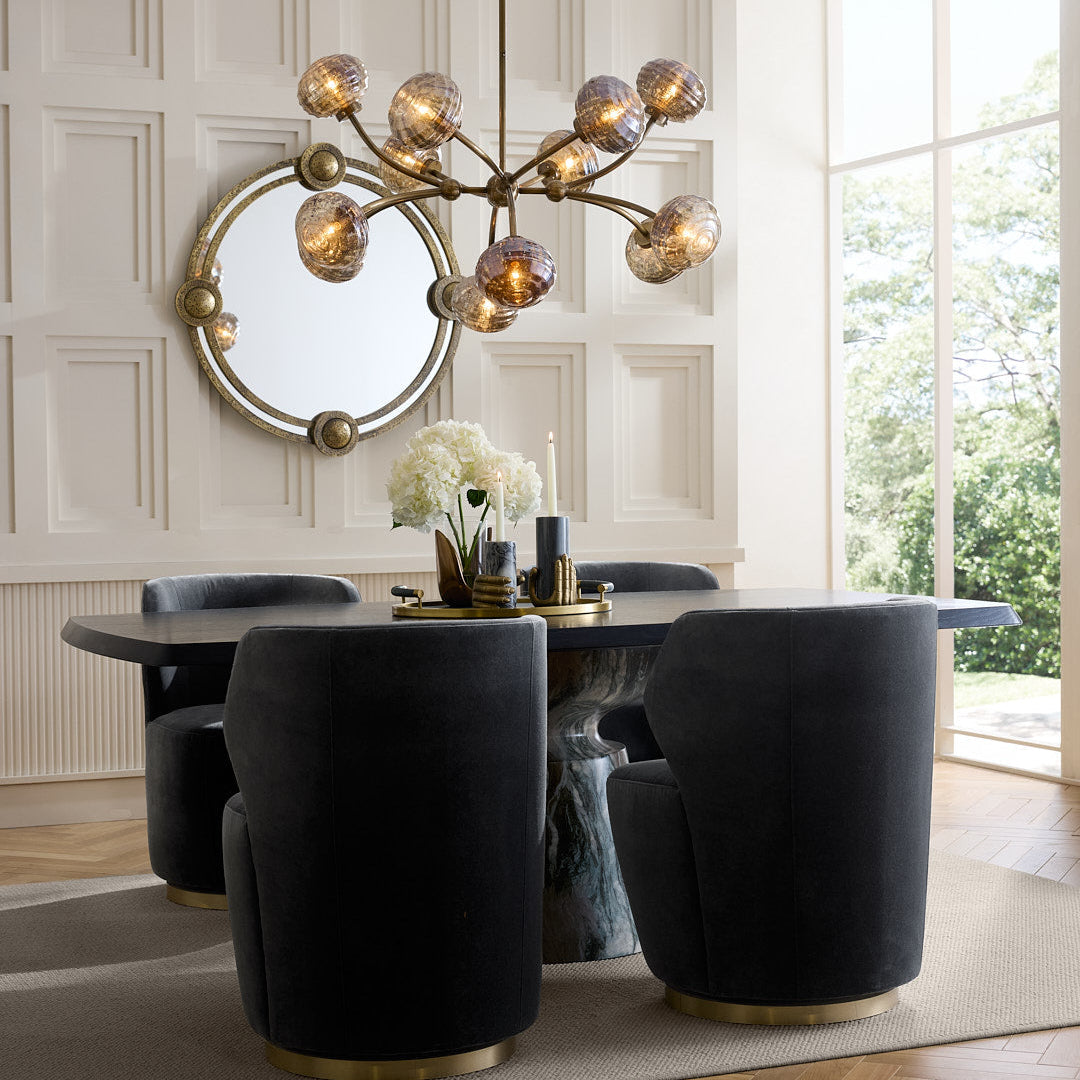 Modern dining room with black chairs, a round mirror, and a chandelier.