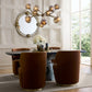 Dining room with a modern chandelier, round mirror, and brown chairs.