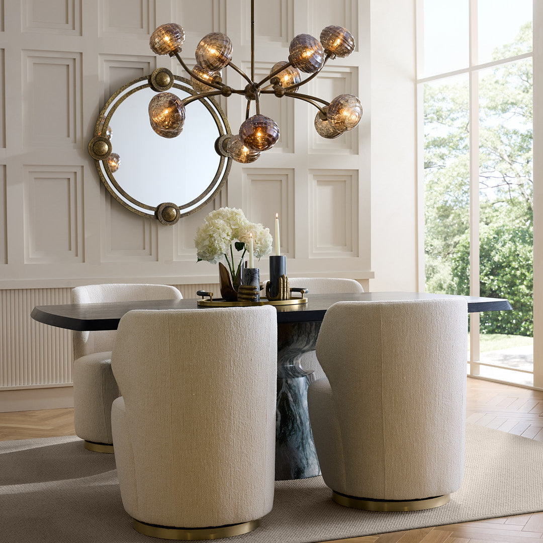 Modern dining room with a chandelier, round mirror, and white chairs.
