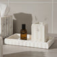 Marble tray with Aesop bottle and toothbrush holder against a tiled wall.