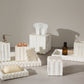 Marble bathroom accessories including a soap dish, tissue holder, and soap on a brown tiled wall background.