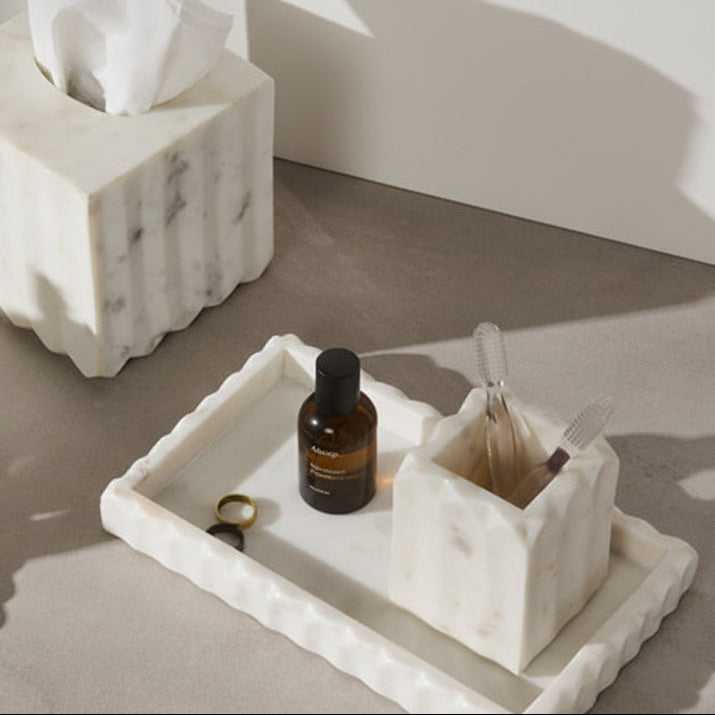 Marble-textured tissue box and tray with skincare products on a neutral background