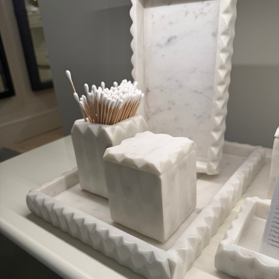 White decorative items including a cube and toothpick holder on a marble surface.