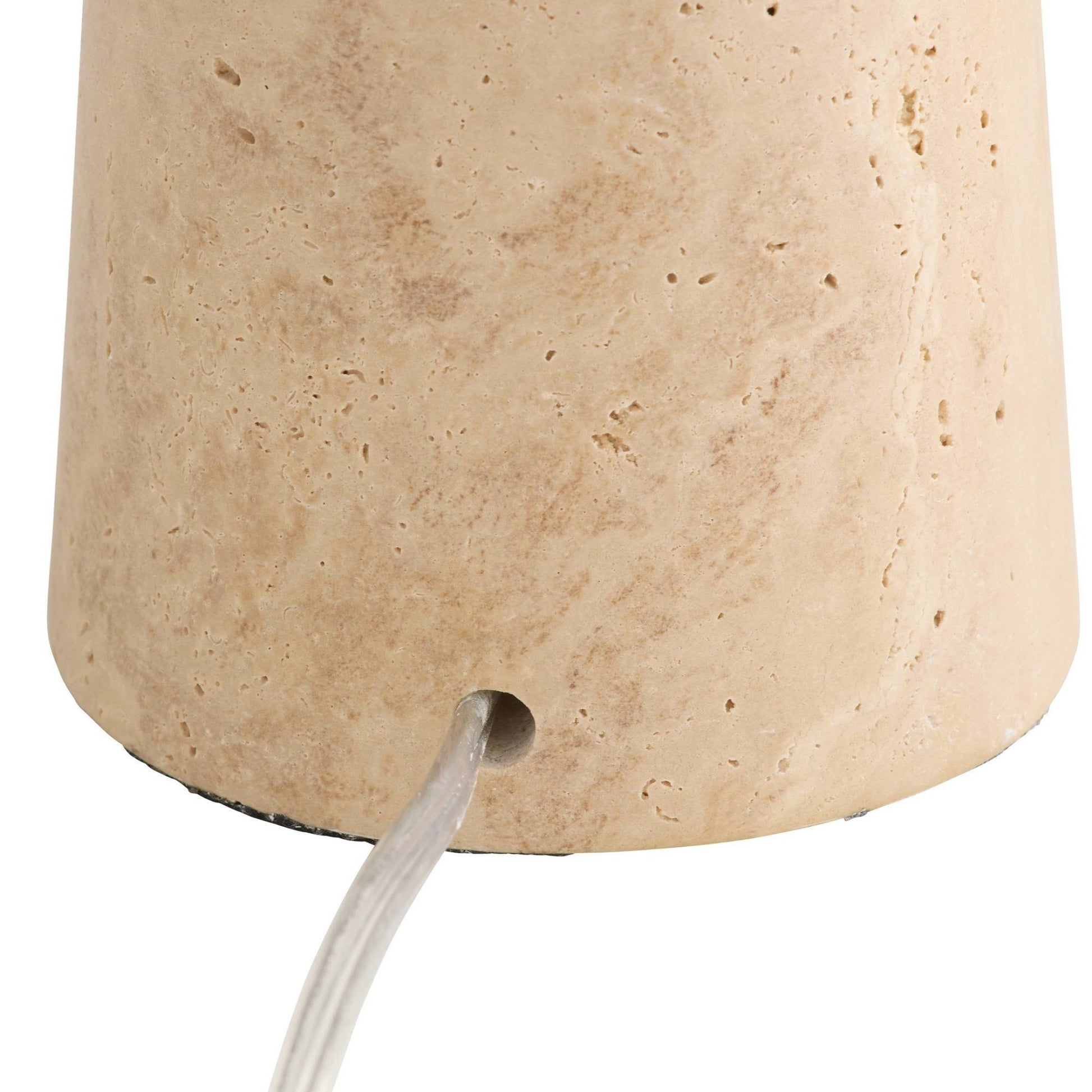 Close-up of a tapered stone or travertine-style lampshade in a warm beige/tan color, showing the textured surface and a small circular opening at the base from which a white cord exits.