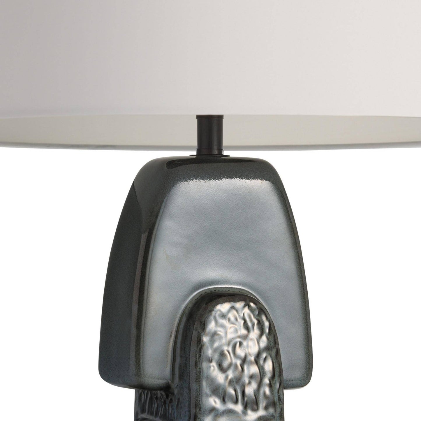 Close-up of a textured lamp base with a white shade on a light gray background