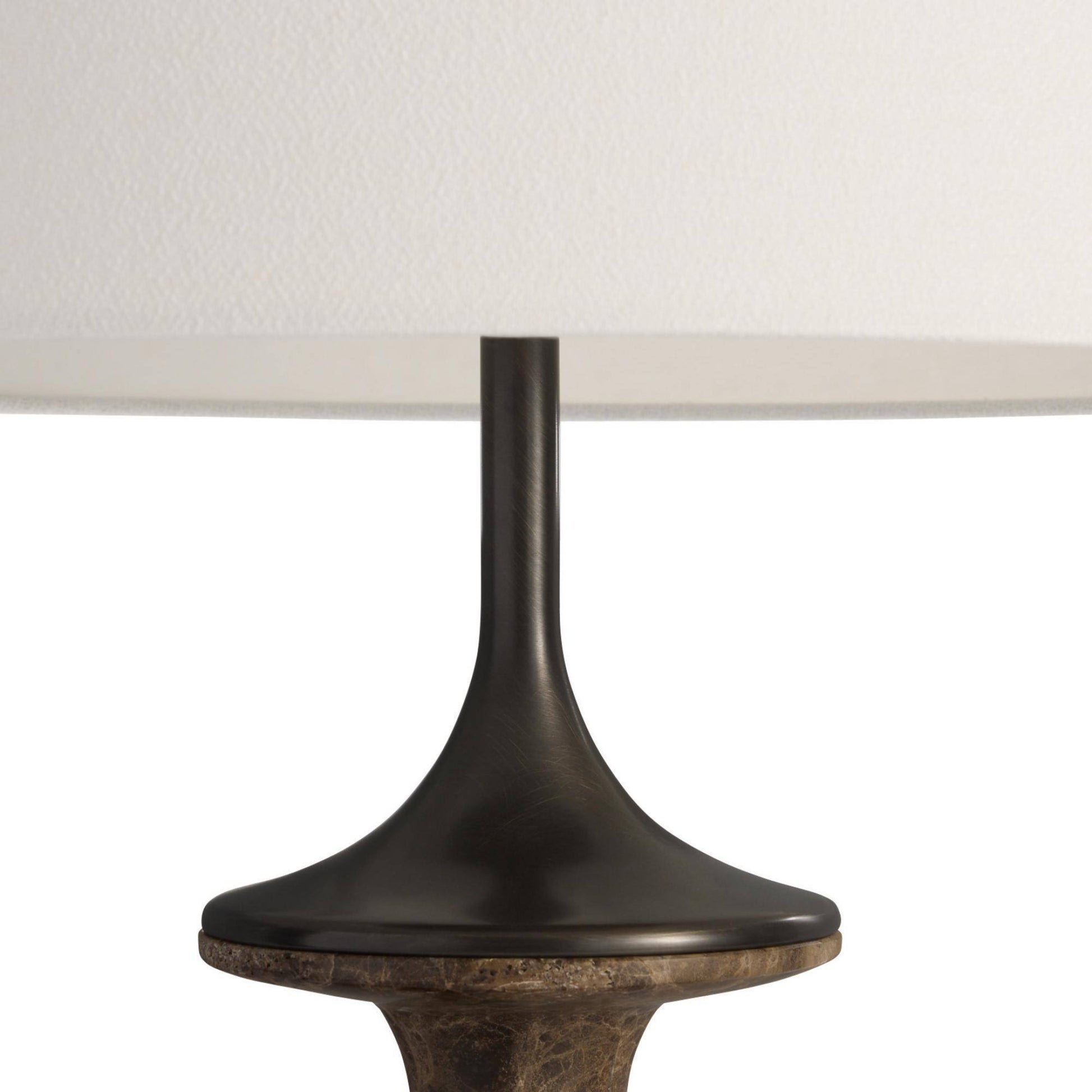 Close-up of a table lamp with a dark bronze base and white shade on a white background