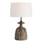 Table lamp with a textured base and white shade on a white background