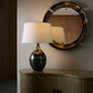 Decorative lamp on a wooden cabinet with a round mirror in the background