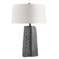 Table lamp with textured gray base and white shade on a white background