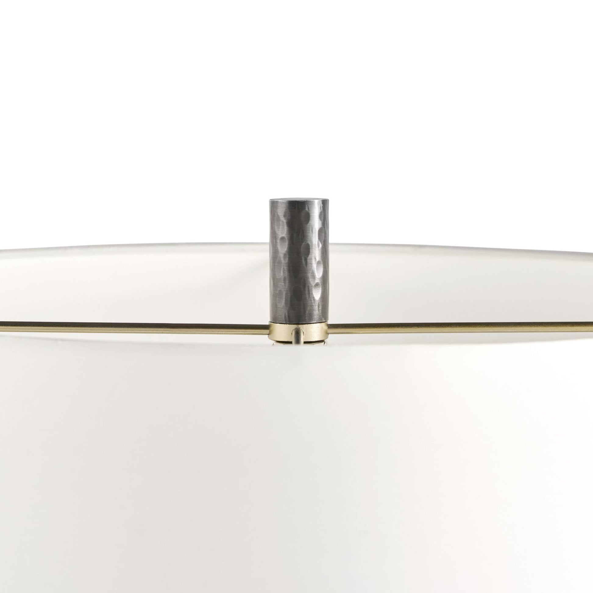 Close-up of a modern lamp shade with a white fabric body, a clear glass top, and a hammered silver metal finial on a brass rod, set against a plain white background.