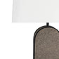Close-up of a table lamp with a white rectangular shade and a dark metal frame holding a textured taupe-gray oval lamp base, shown against a white background.