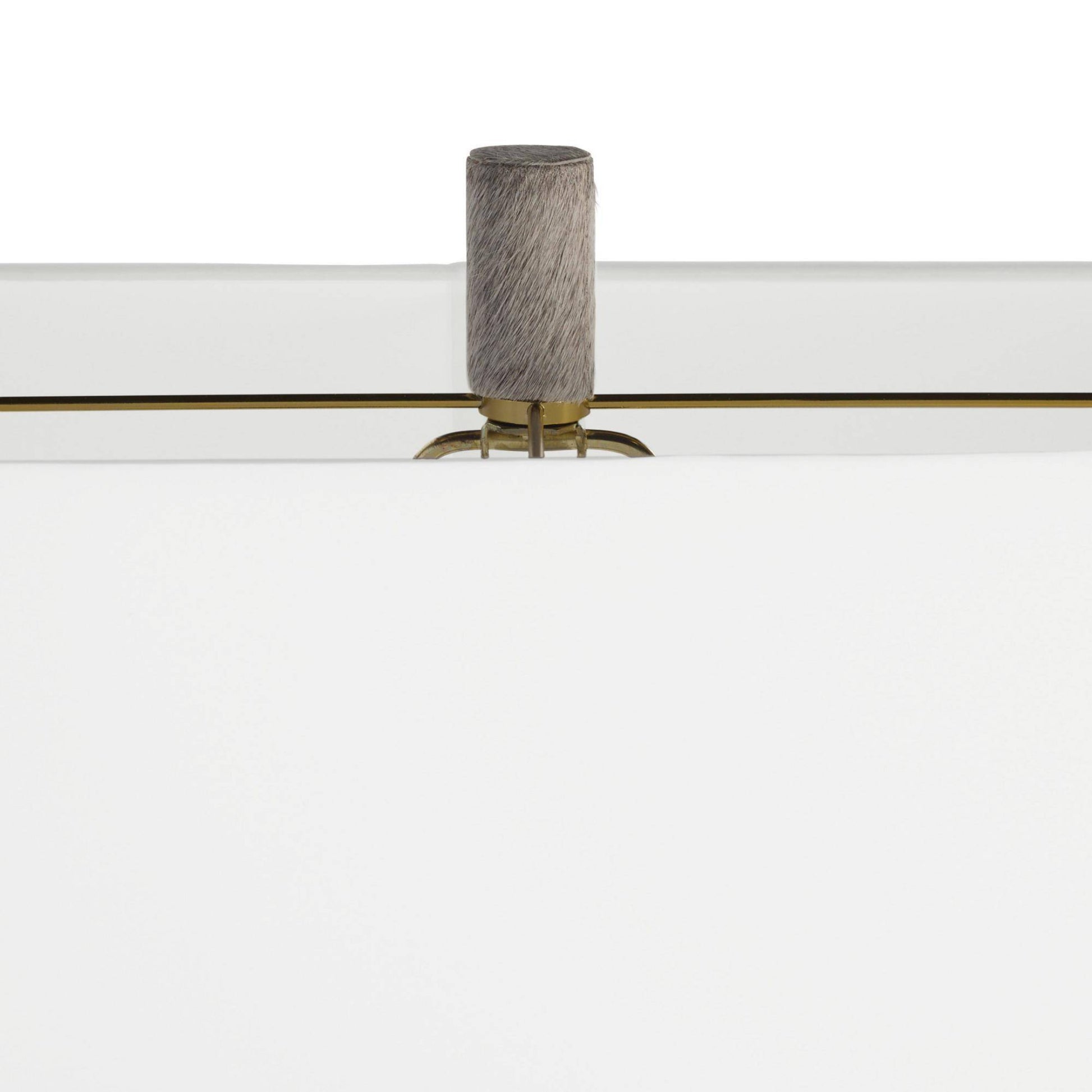 Close-up of a modern white furniture piece with a cylindrical gray textured handle and a thin gold horizontal accent line.