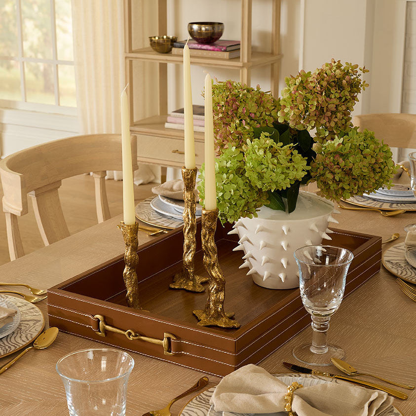 Decorative table setting with candles, flowers, and a wooden tray.