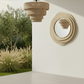 Beige chandelier and round mirror on a white wall with outdoor view