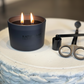 Candle in a black container with 'RATENFELD' branding on a textured surface.