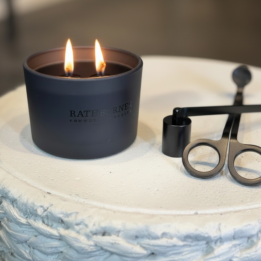 Candle in a black container with 'RATENFELD' branding on a textured surface.